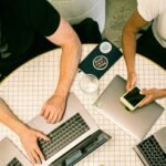 Top view of a team collaborating with laptops, phones, and notes in a modern office.